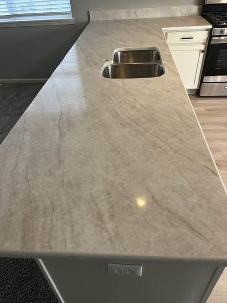 Kitchen countertop with a built-in stainless steel sink and light marble-pattern surface.
