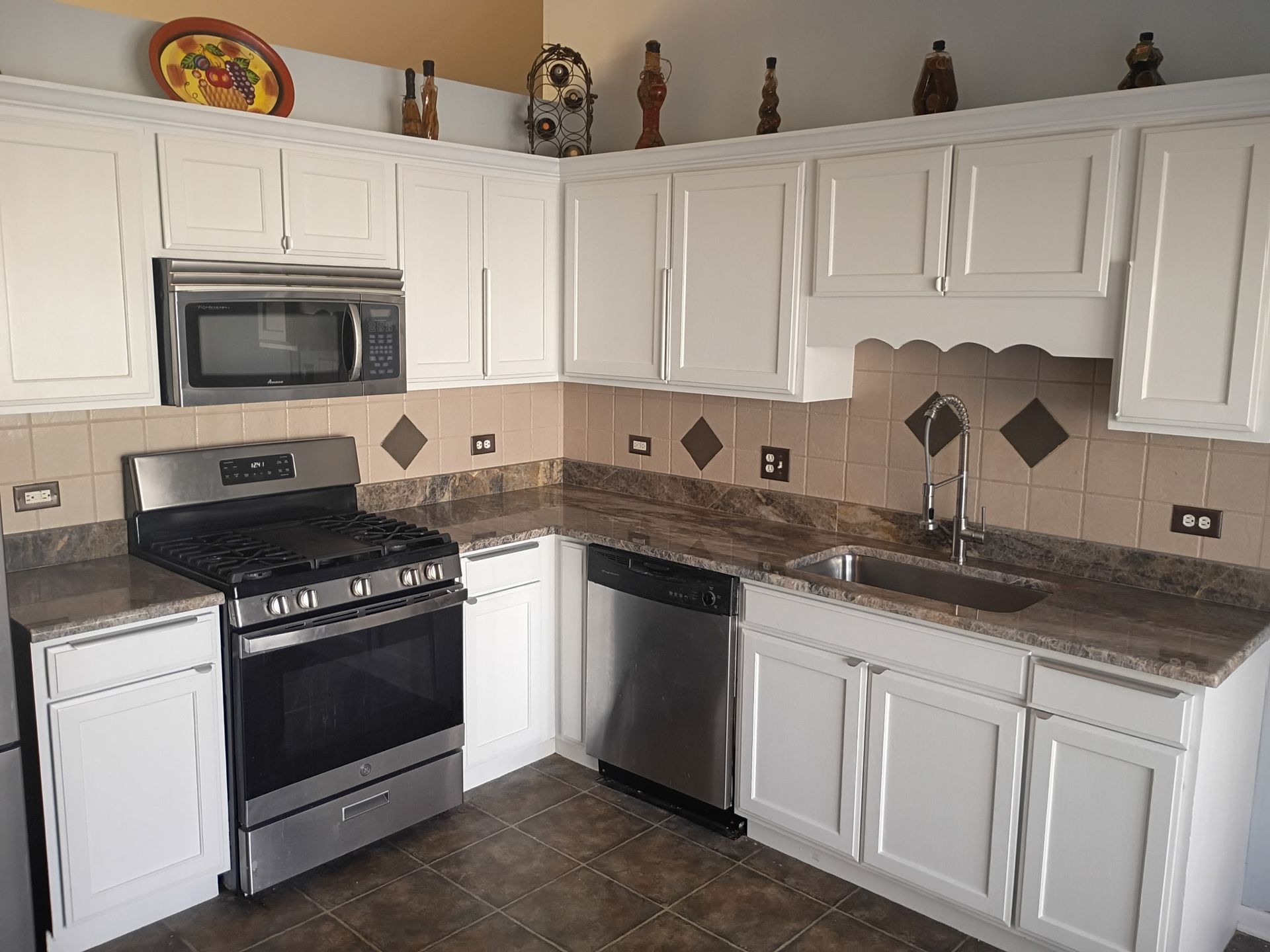 Kitchen with white cabinets, stainless steel appliances, and granite countertops in an L-shaped layout