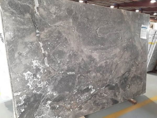 Large gray marble slab leaning upright in an industrial warehouse setting