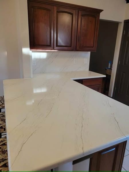 Kitchen with white marble-look countertop and dark wood cabinets along the wall