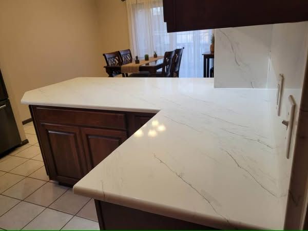 Kitchen island with white marble countertop and dark wood cabinets in a tiled room