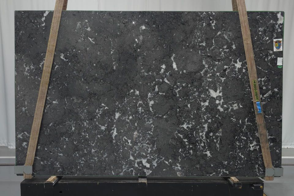 Dark gray speckled stone slab held upright by wooden braces in a workshop.