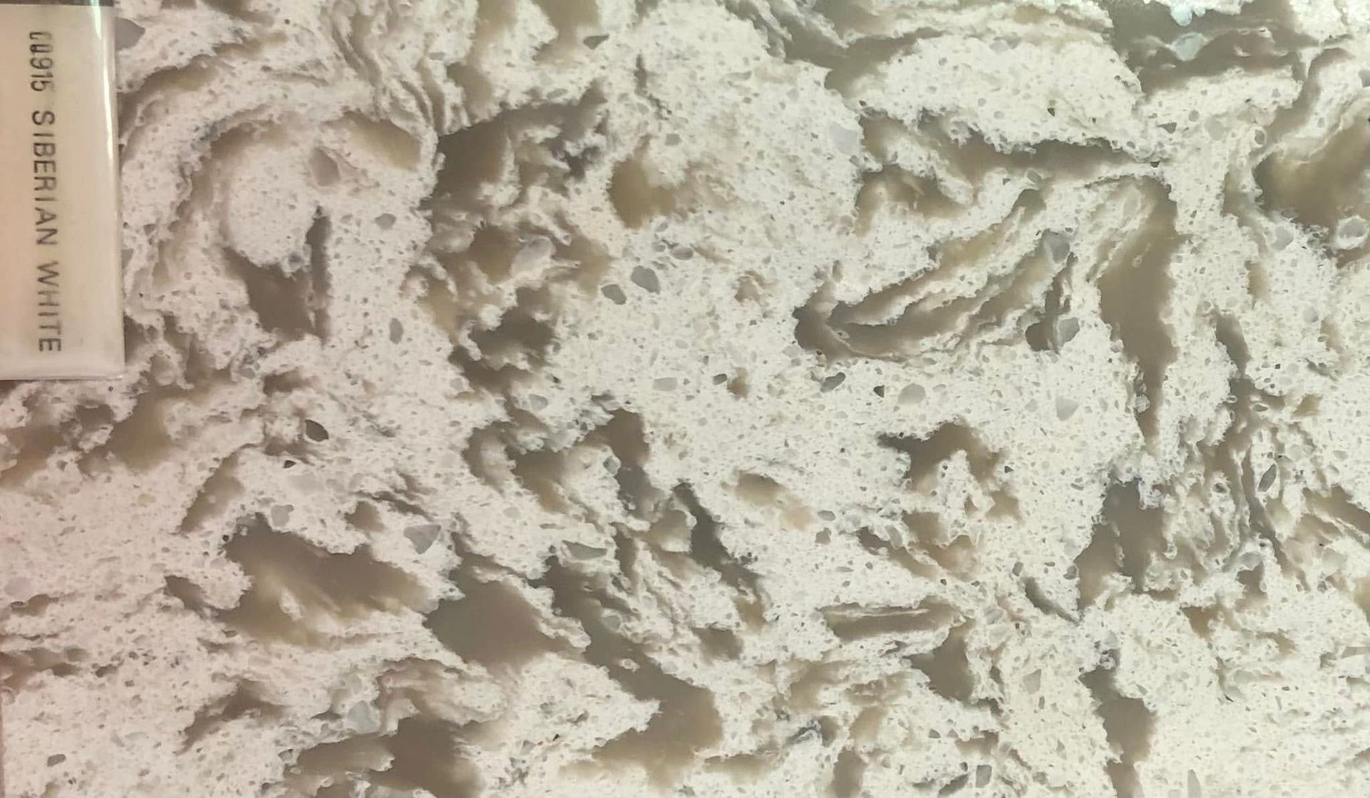 Close-up of creamy white textured fabric or faux fur with a beige tag on the left edge