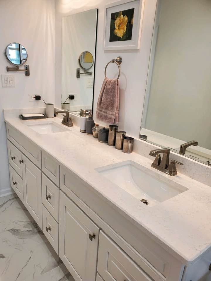 Modern white bathroom vanity with double sinks, mirrors, faucets, and marble-style floor and countertop