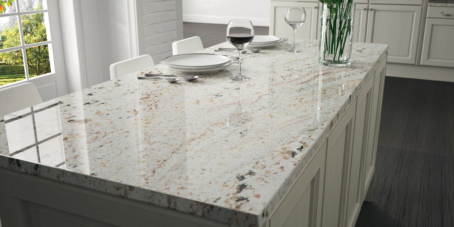 Sunlit kitchen island with white granite countertop, dishes, and a vase of flowers.
