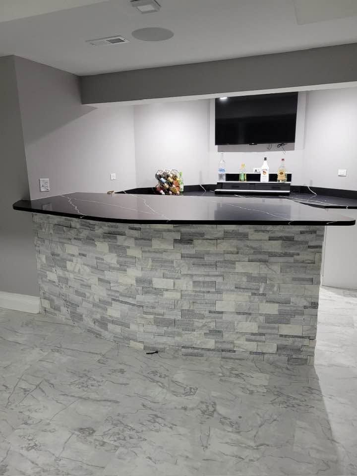 Modern kitchen with stone island, dark countertop, and white cabinetry.