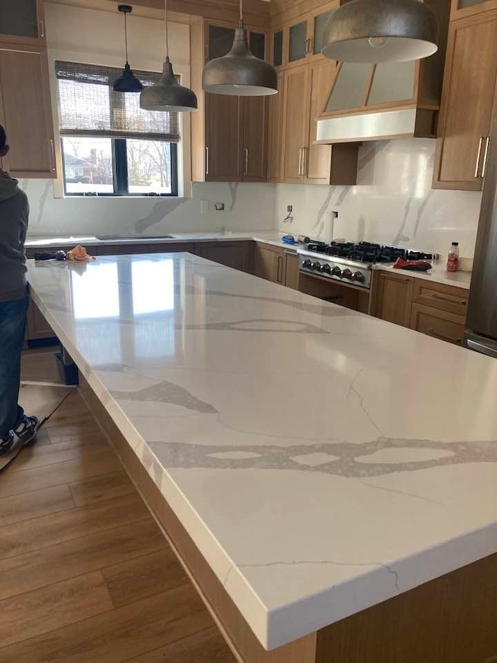 Bright modern kitchen with large white island, wood floors, and hanging pendant lights