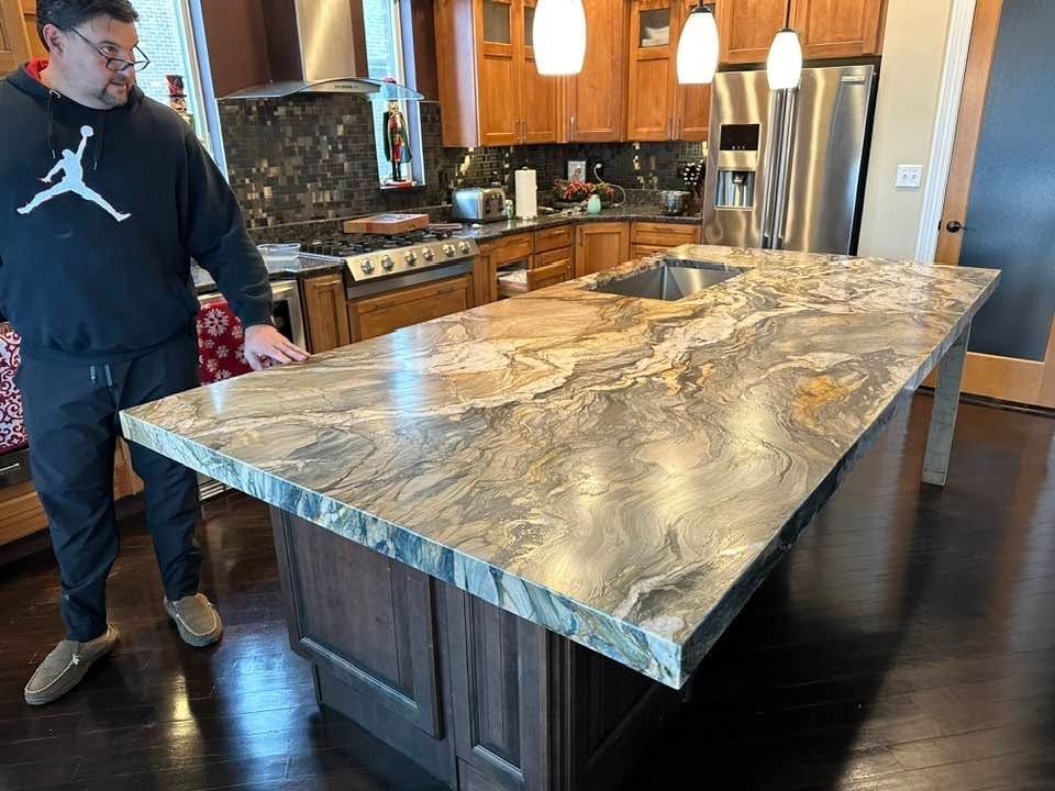 Man standing beside a large marble kitchen island in a warm-toned home kitchen