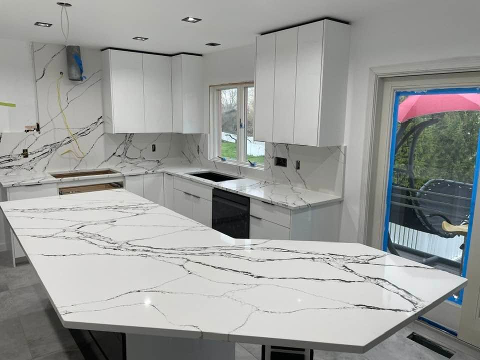 Modern kitchen with white cabinets, marble-look island, and unfinished walls under renovation