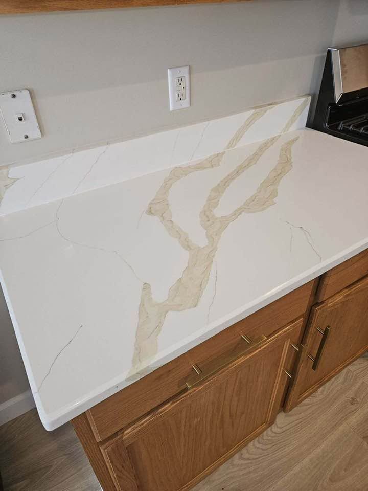 White marble-look countertop slab leaning against a wall above wooden cabinets.