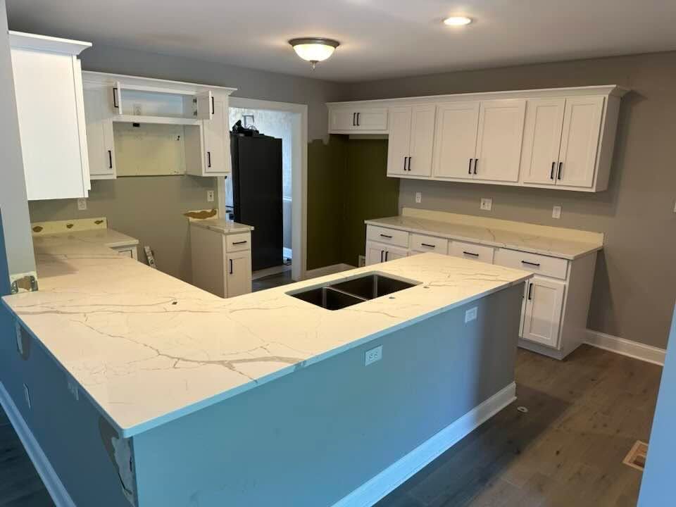 Bright modern kitchen with white cabinets, blue island, and white countertops