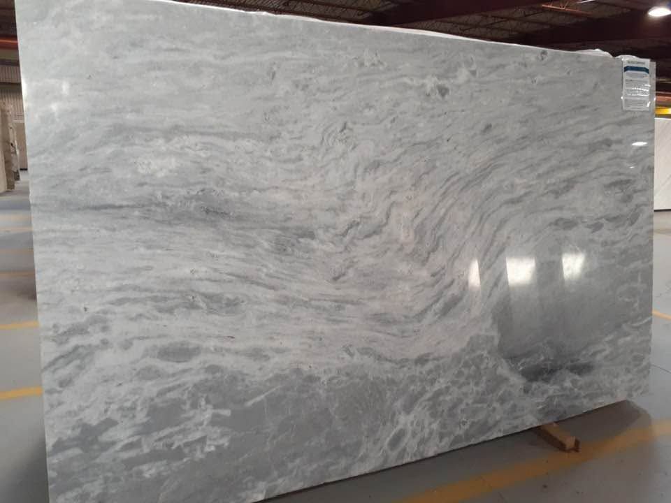 Large polished gray marble slab with white veining on a warehouse pallet.