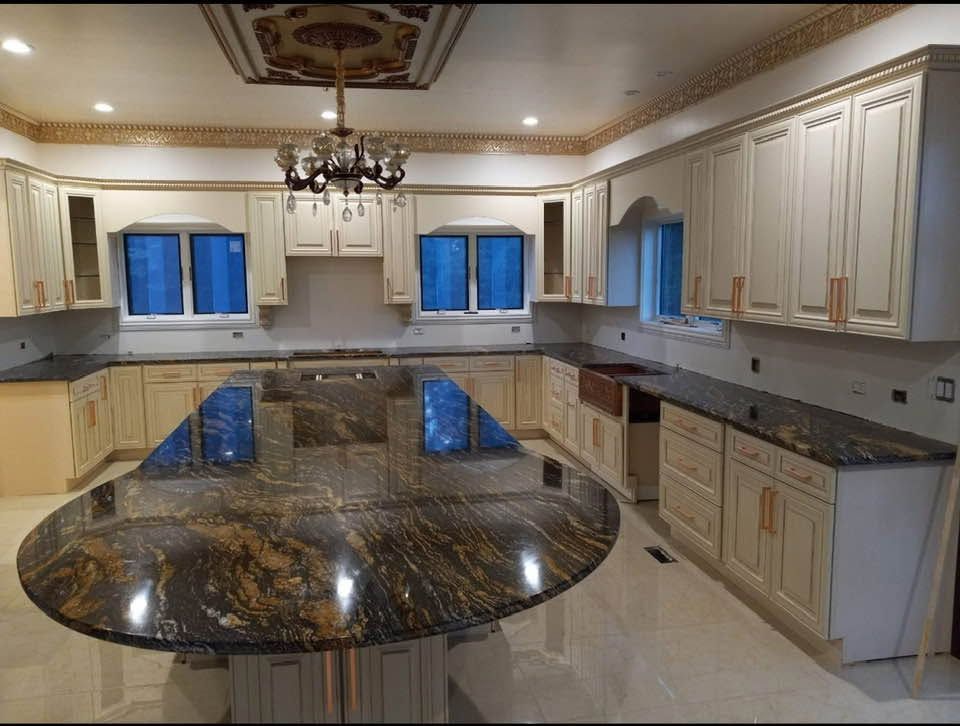 Elegant cream kitchen with dark granite island, chandelier, and blue-lit windows