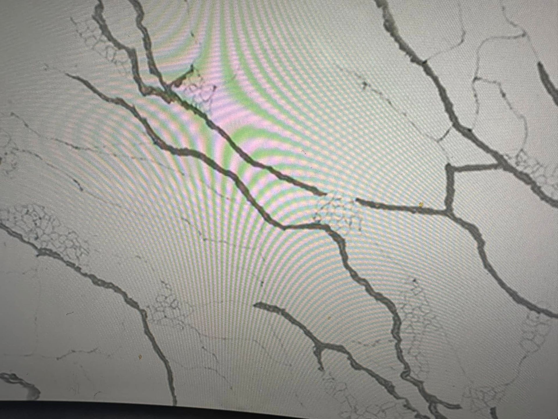 Cracked white painted wall with dark branching fissures and a faint pinkish stain near the center