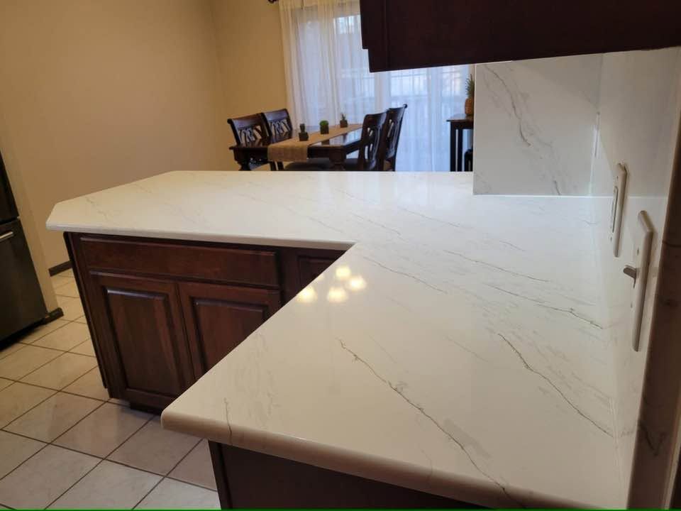 Kitchen counter with white marble-look countertop and dark wood cabinets, overlooking a dining area.