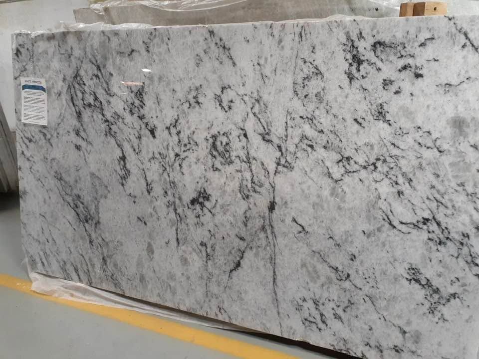 Large slab of white-and-gray speckled stone standing upright on a warehouse floor.