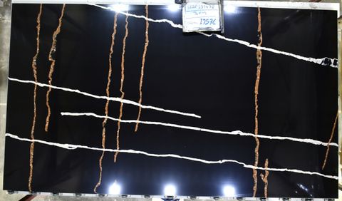 Dark reflective wall with tangled white and orange string lights and a small sign at the top center