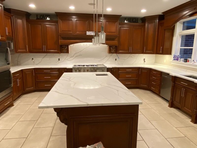 Spacious kitchen with dark wood cabinets, white marble island, and beige tile floor
