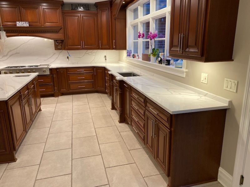 Empty kitchen with dark wood cabinets, white countertops, and beige tile floor