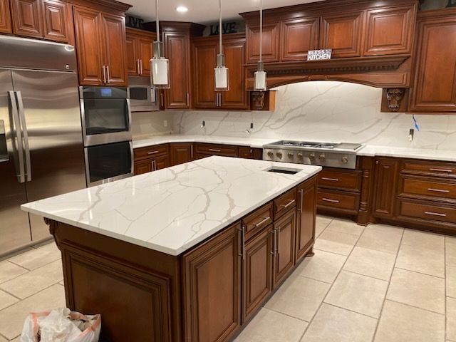 Modern kitchen with dark wood cabinets, stainless appliances, and a large white island countertop