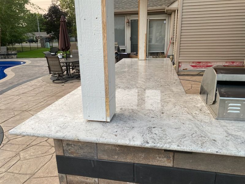 Back patio with white granite bar, stone pavers, pool, and sliding glass doors