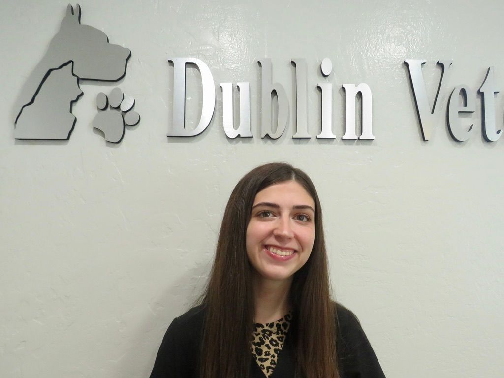 A woman is smiling in front of a dublin vet sign.