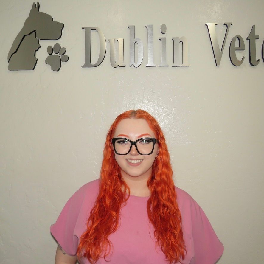 A woman with red hair and glasses stands in front of a dublin veterinary sign