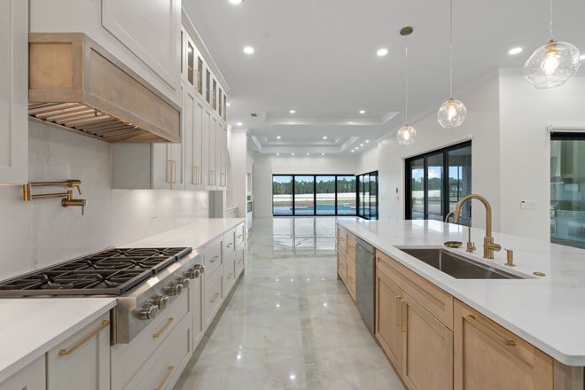 Bright modern kitchen with white countertops, light wood cabinets, marble floor, and large windows