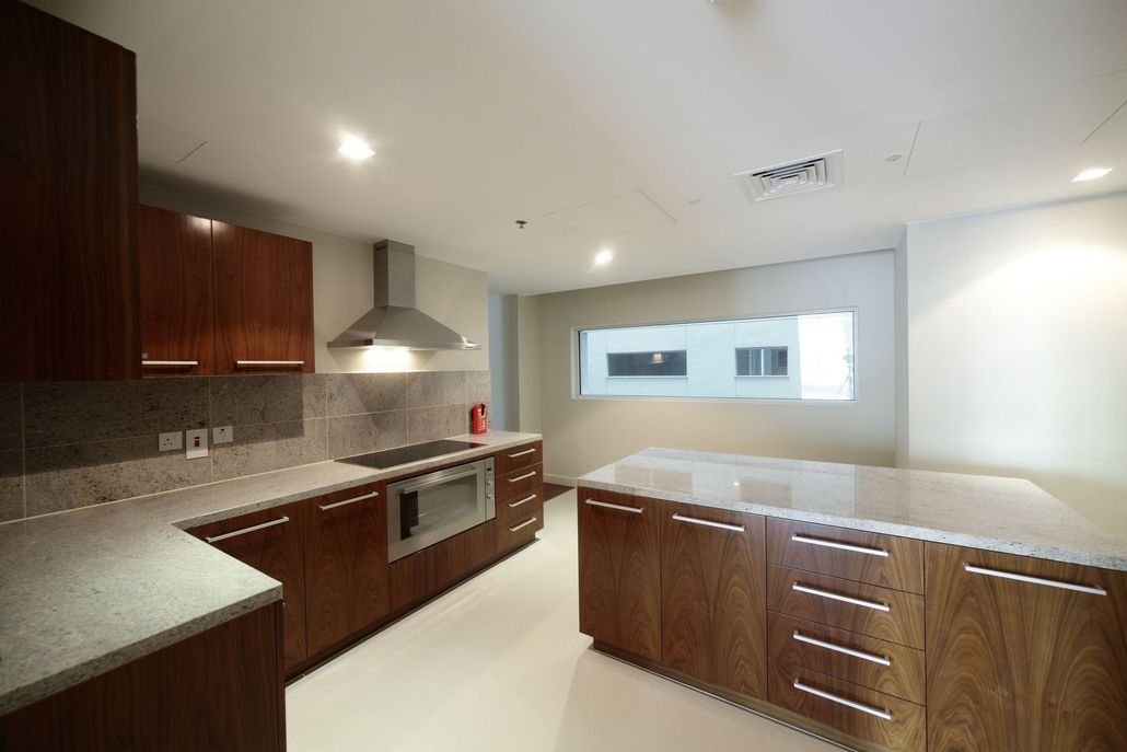 A modern kitchen with dark wood cabinets, a stainless steel range hood and oven, and a white kitchen island.