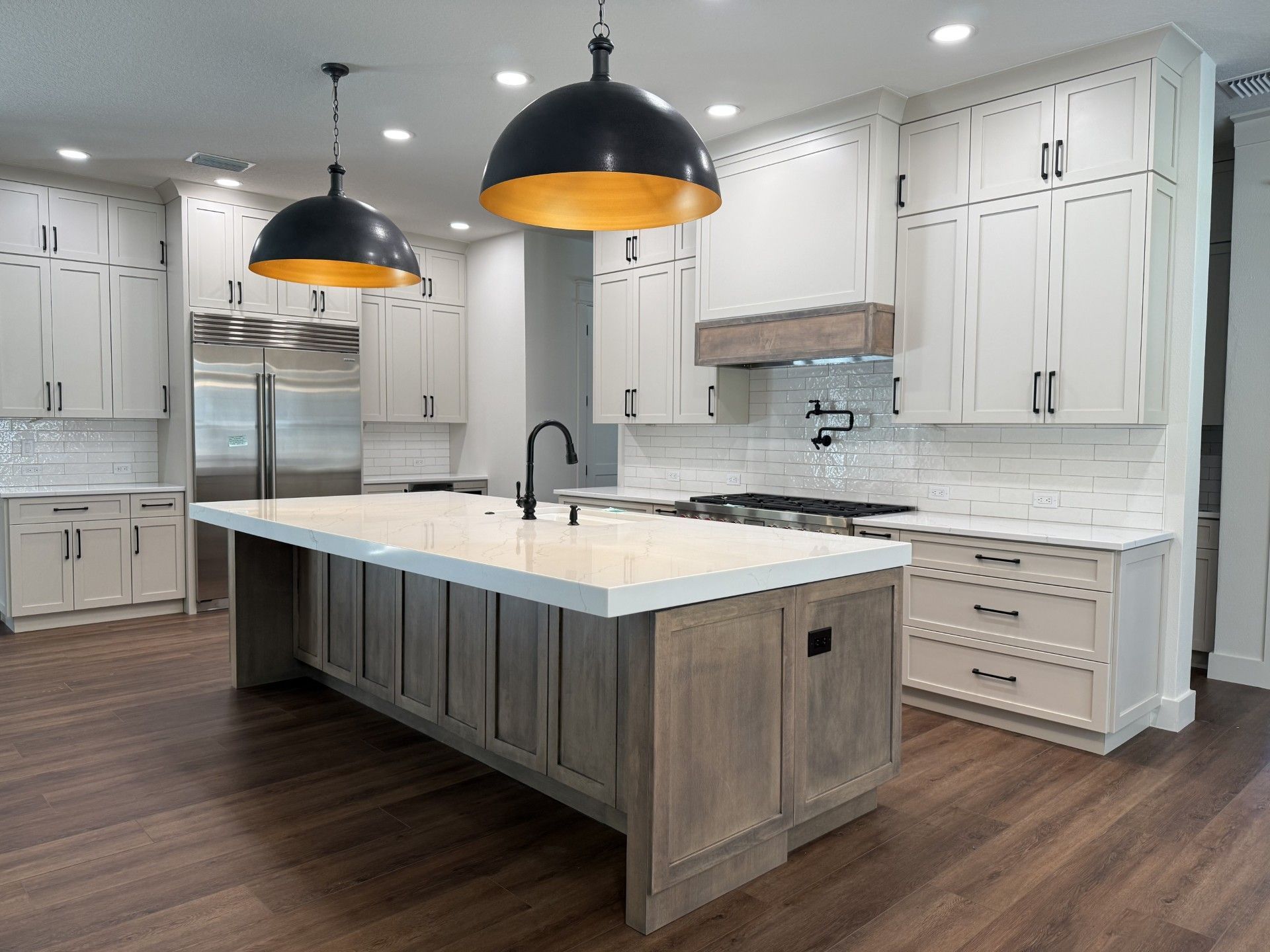 Bright modern kitchen with white cabinets, wood island, and black pendant lights