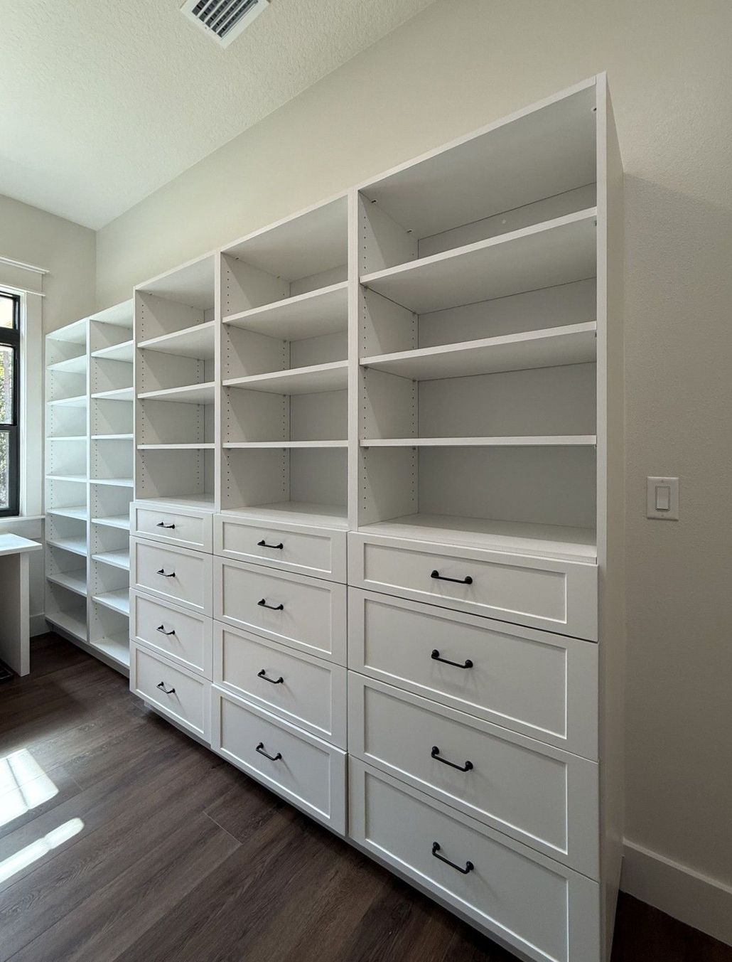 White built-in shelving and drawers in a bright walk-in closet or dressing room