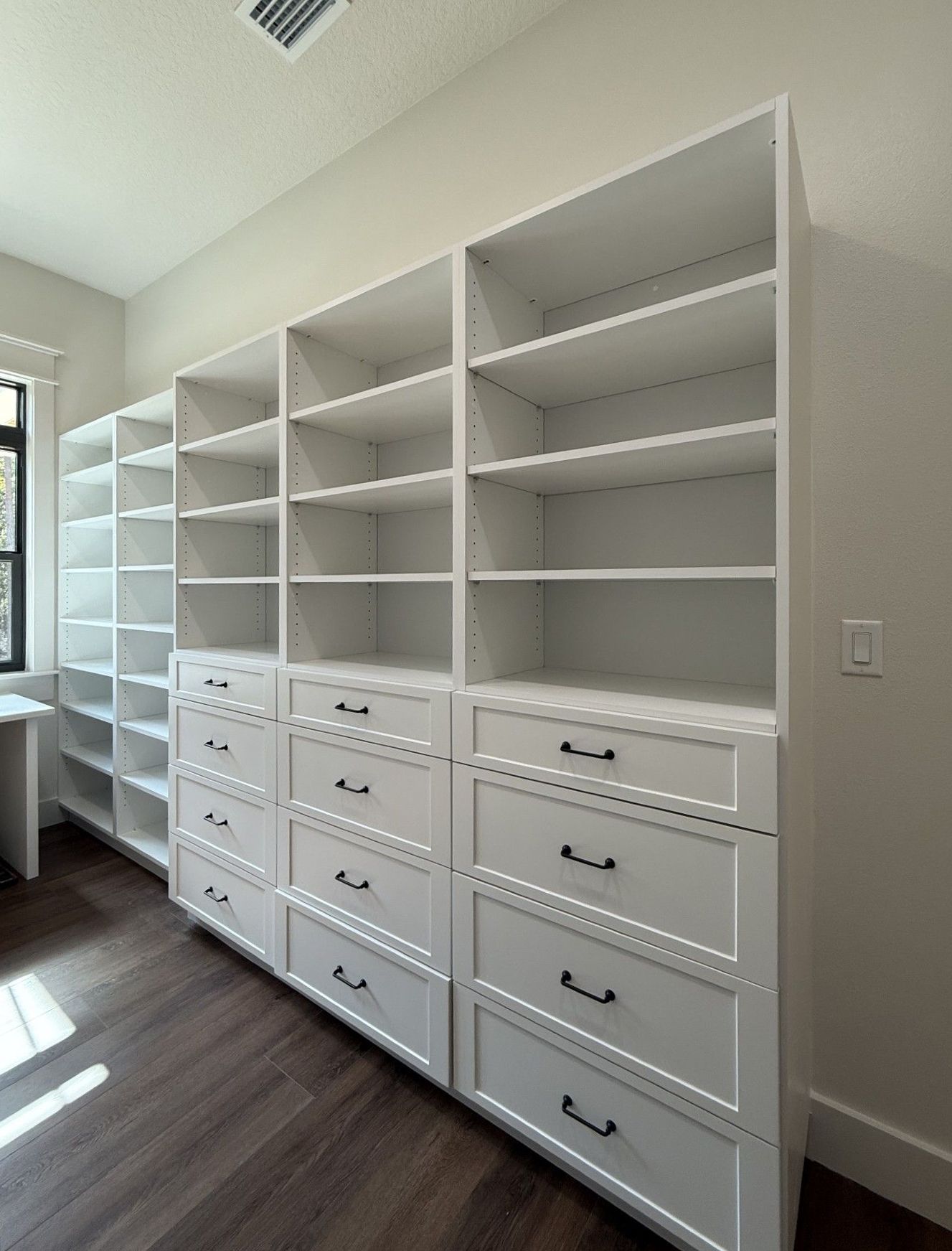 White built-in shelving and drawers in a bright walk-in closet or dressing room