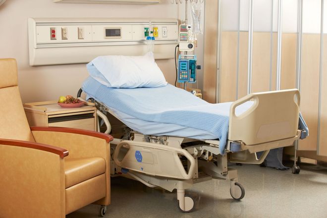 Hospital room with an adjustable bed, a recliner, and medical equipment.