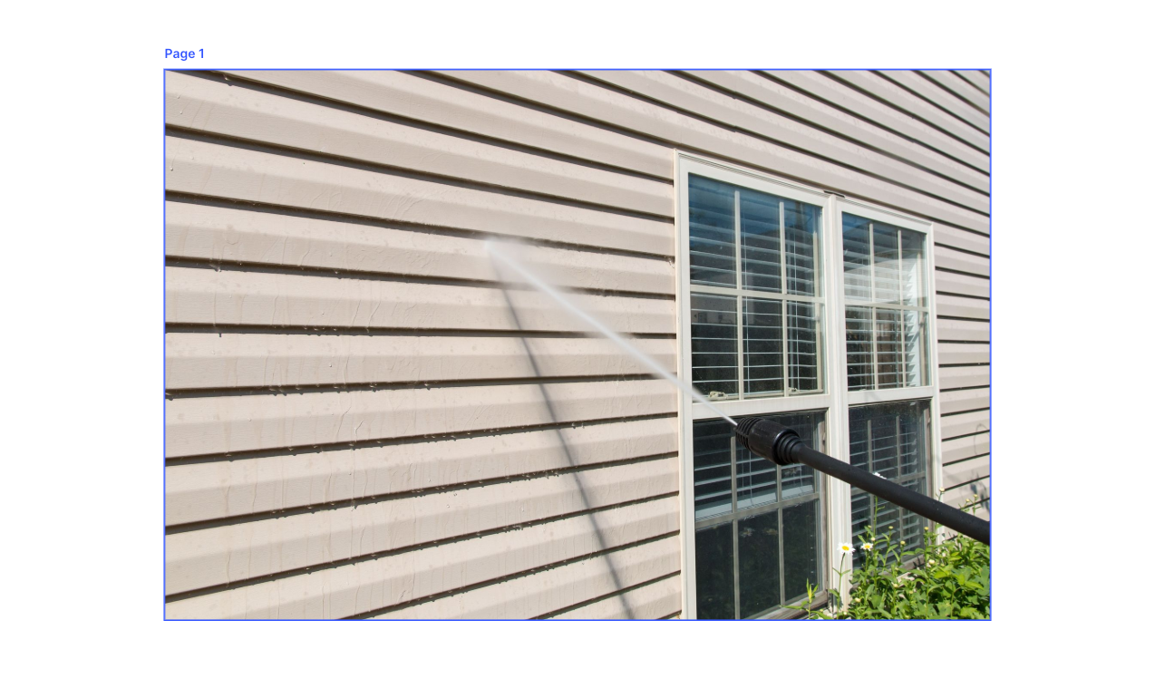 A person pressure washes a house with tan siding near a window.