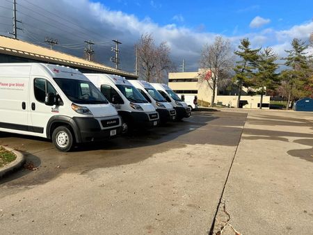 A row of white vans are parked in a parking lot.