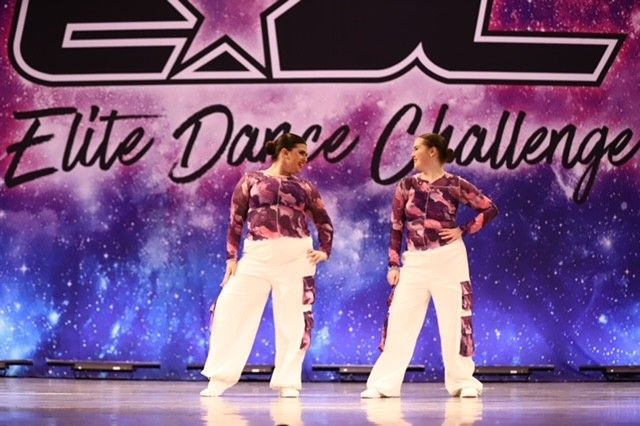 Two dancers posing onstage at Elite Dance Challenge with a starry purple backdrop