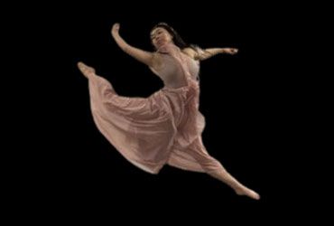 Dancer in a flowing pink dress mid-leap against a black background