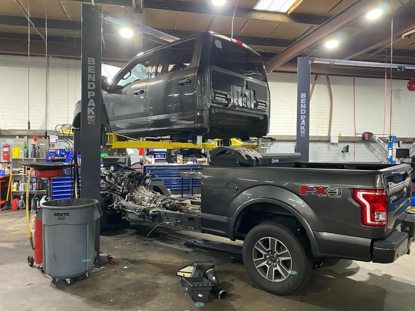 A truck is sitting on top of a lift in a garage.