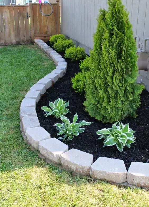 A garden with a brick border and plants in it.