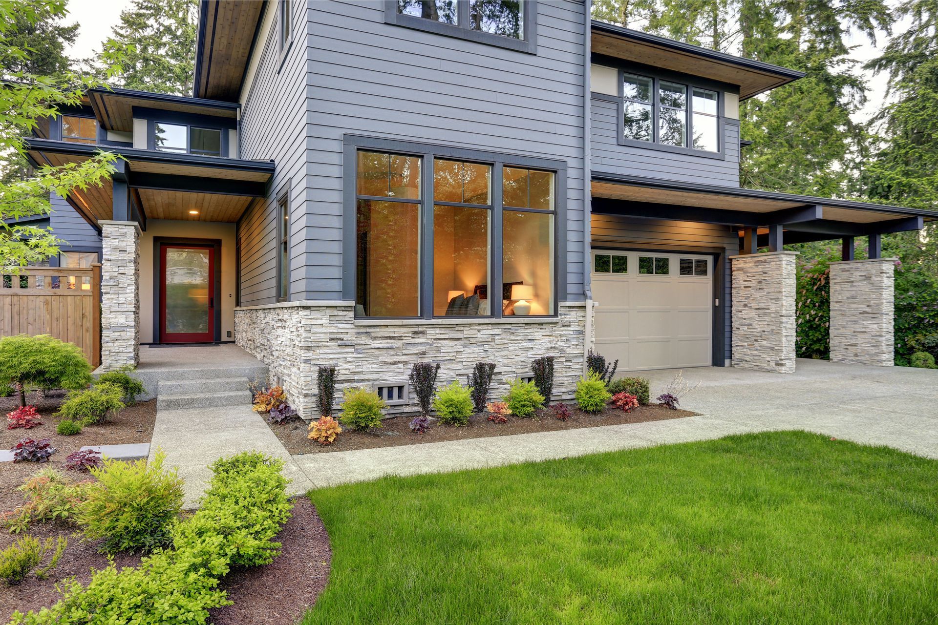Modern two-story brick house with a manicured lawn, landscaped front yard, and attached garage