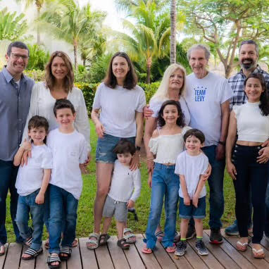 A large family is posing for a picture together on a wooden deck.