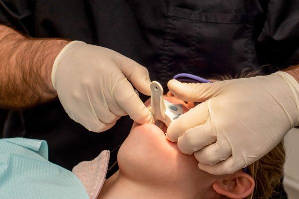A dentist is examining a child 's teeth in a dental office.
