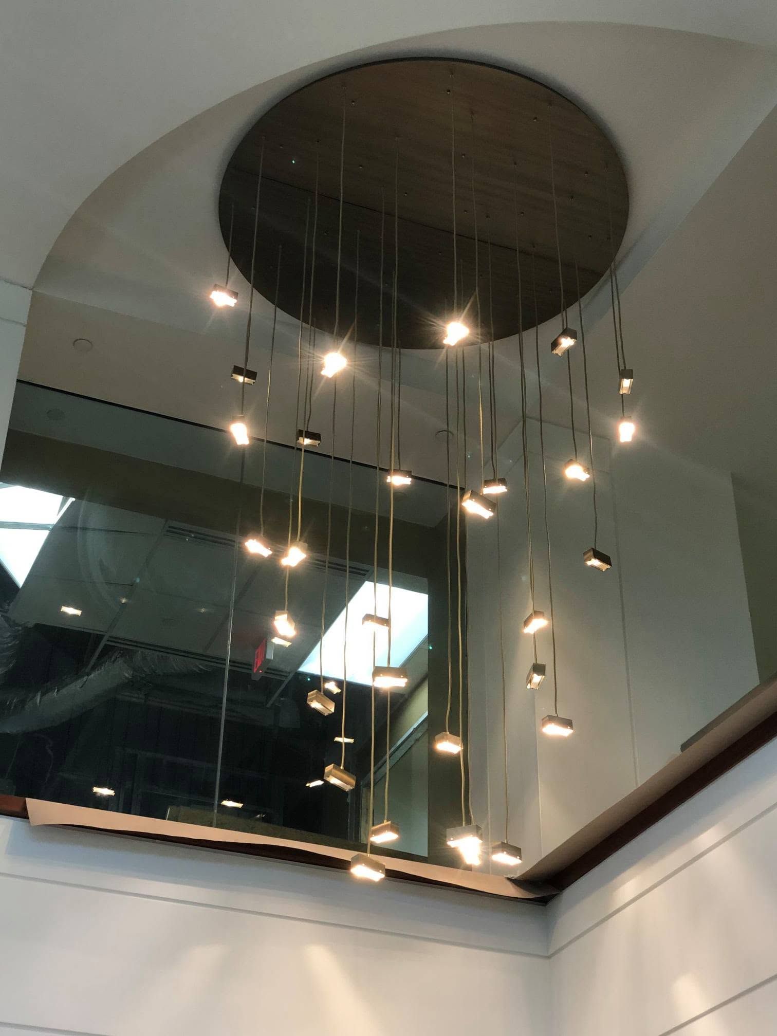 Modern interior with a large circular ceiling cutout and hanging pendant lights reflected in glass.
