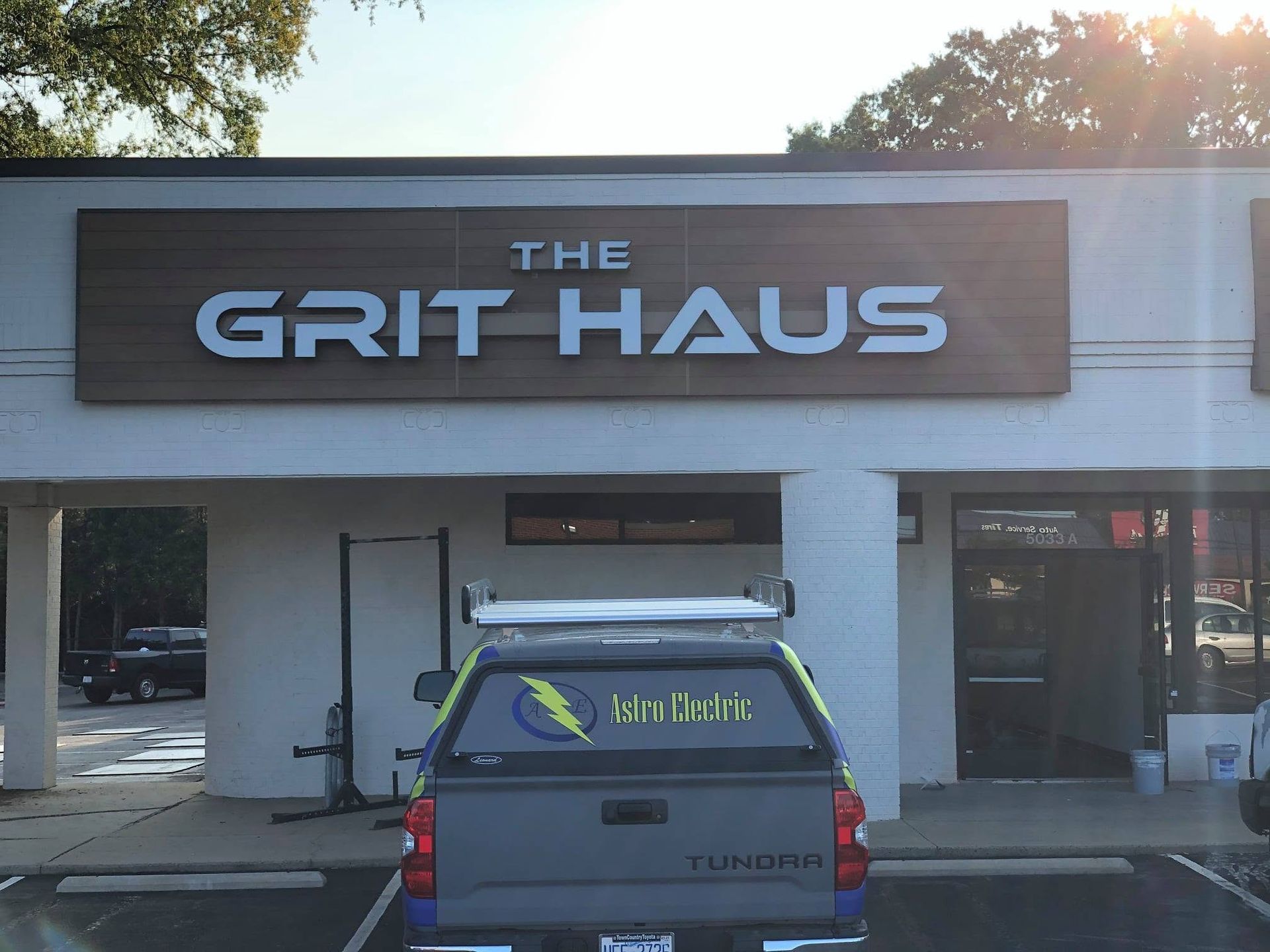 Storefront sign reading “The Grit Haus” above a parked blue pickup truck