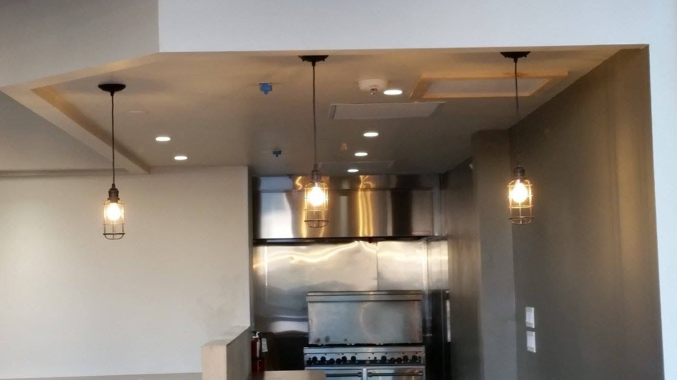 Modern kitchen with pendant lights, stainless steel stove, and open pass-through window to another room