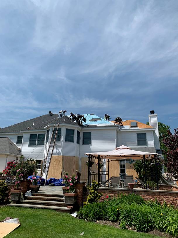 A large white house with a roof being installed.