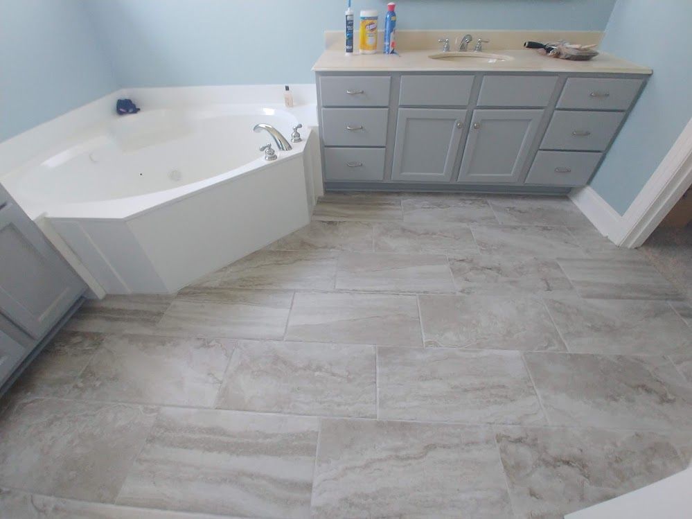A bathroom with a tub, sink, and cabinets.
