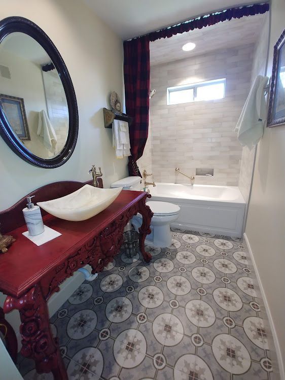A bathroom with a sink, toilet, tub, and mirror.