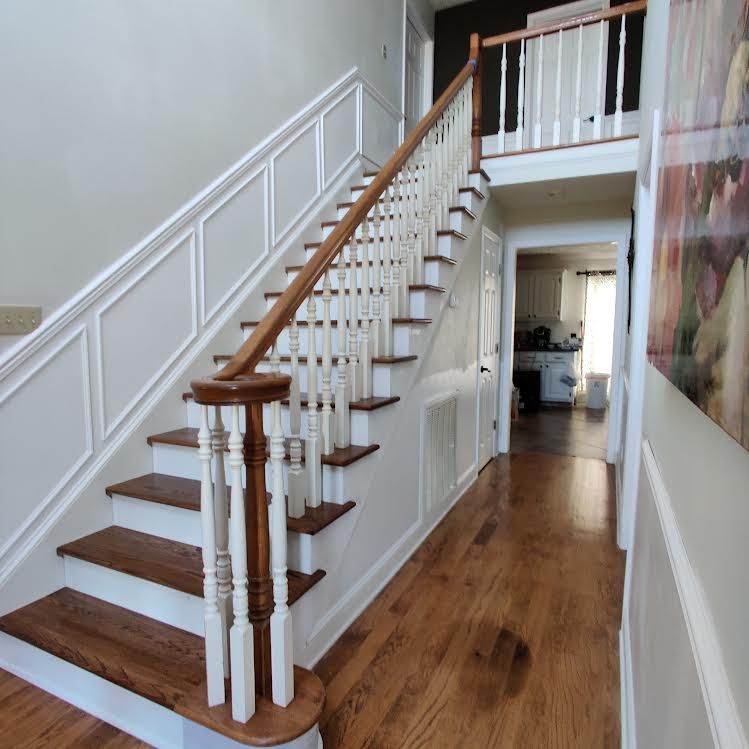 A staircase with wooden steps and white railing in a hallway