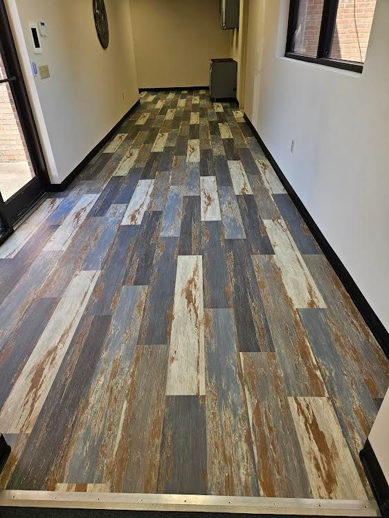 A hallway with a wooden floor and a window.